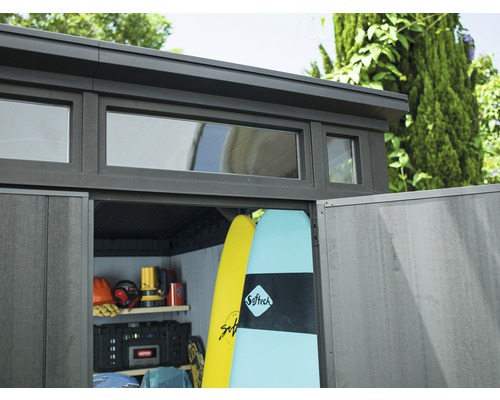 Gartenschuppen mit Fenstern und geöffneter Tür, gefüllt mit Surfbrettern und Gartengeräten