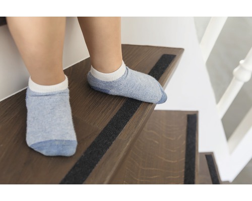 Enfant sur un escalier avec des bandes antidérapantes.