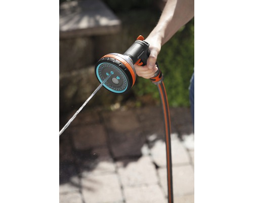 Une main tient un pistolet d''arrosage d''où sort de l''eau.