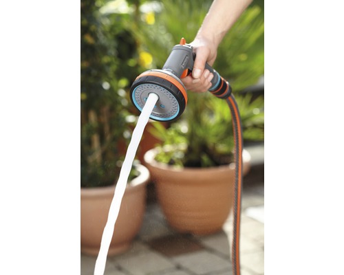 Une personne tient une lance d''arrosage multifonction Gardena avec jet d''eau