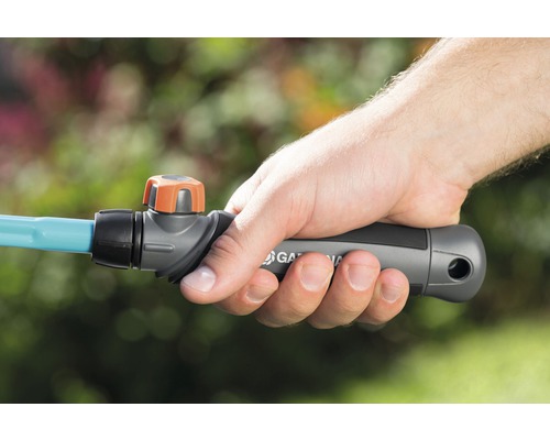 Une main tient un tuyau d''arrosage Gardena avec une vanne d''arrêt.