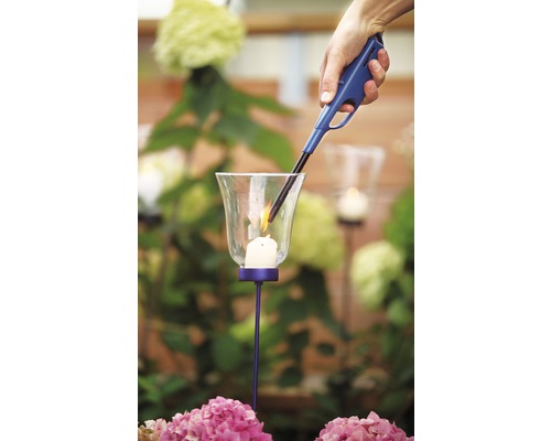 Une main allume une bougie dans un photophore avec un briquet à allumage long.