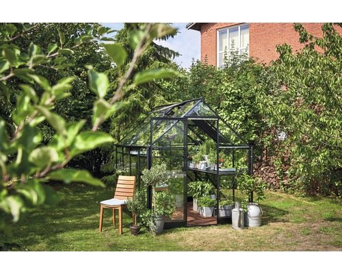 Serre avec plantes sur une pelouse à côté d''une chaise en bois