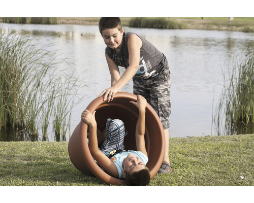 Zwei Jungen spielen mit einem grossen Pflanzgefäss im Freien.