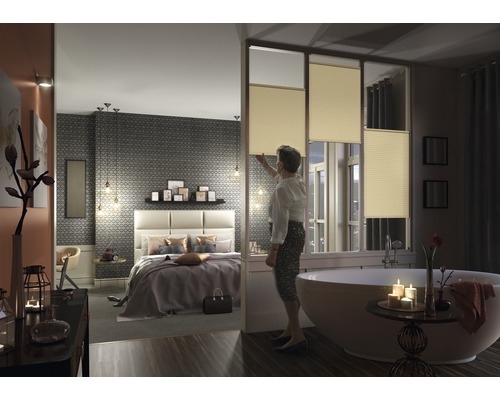 Helles Schlafzimmer und Badezimmer mit Plissee-Fenstern, getrennt durch eine Trennwand.