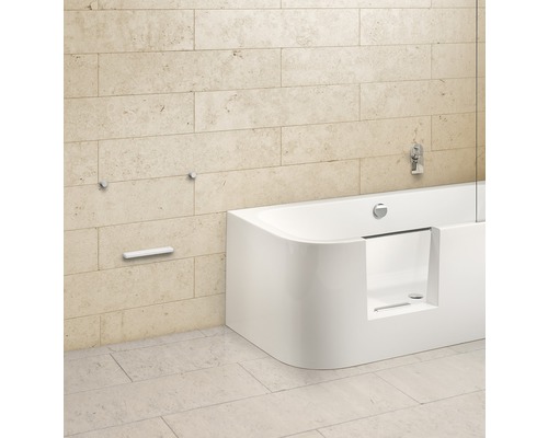 Elegantes Badezimmer mit Badewanne und Armaturen vor einer Steinwand.