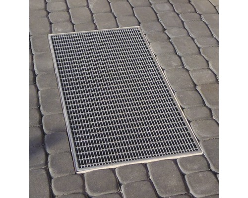 Vue de dessus d''une rigole de cour rectangulaire avec grille, intégrée dans des pavés.