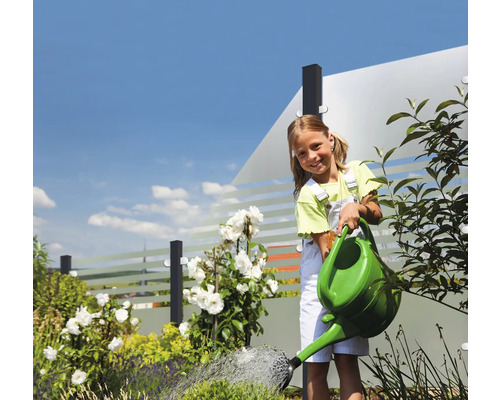 Fille arrosant les plantes du jardin avec un arrosoir