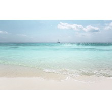 Plage de sable et eau turquoise avec voilier au loin