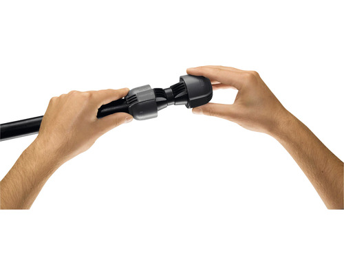 Deux mains montent un raccord noir sur un tuyau noir.