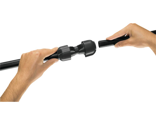 Une personne raccorde un tuyau noir à un raccord droit.