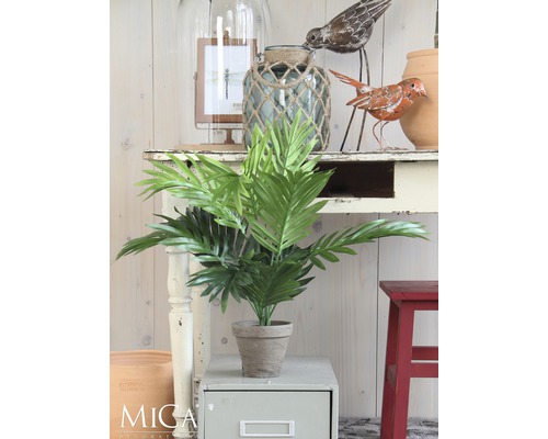 Plante artificielle décorative en pot sur une table d''appoint, entourée d''autres éléments de décoration.