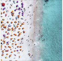 Luftaufnahme eines Strandes mit Menschen und Sonnenschirmen