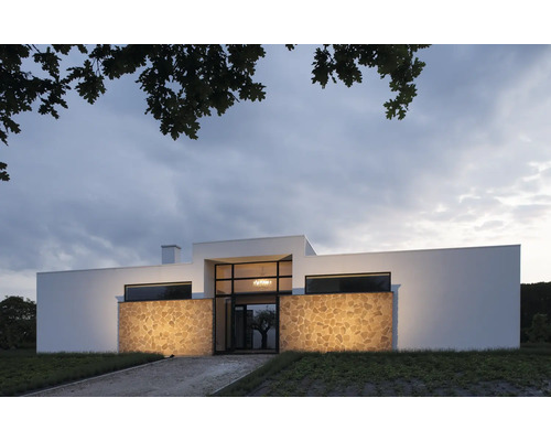 Maison moderne avec façade en pierre naturelle et grandes fenêtres.