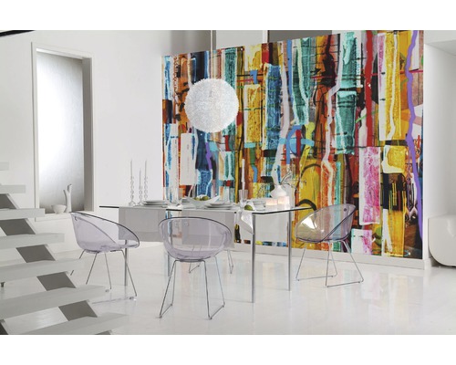 Salle à manger moderne avec une table en verre et des chaises transparentes devant un papier peint coloré.