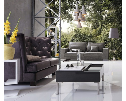 Salon avec canapé, fauteuil, table basse et lampadaire devant un papier peint forêt