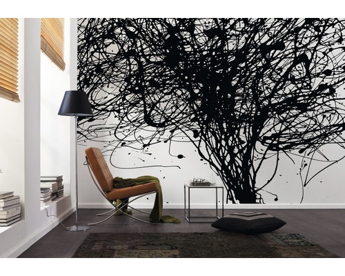 Salon avec mur de taches de peinture noire, fauteuil, lampadaire et tapis