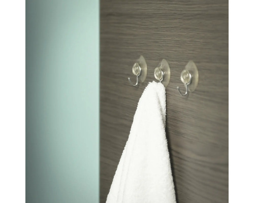 Trois crochets transparents avec ventouse et une serviette blanche sur un mur en bois