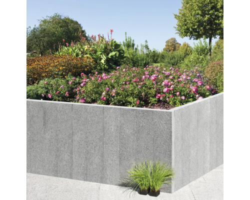 Jardinière surélevée en pierre avec plantes et arbustes fleuris dans le jardin