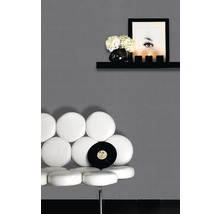 Szene mit einem weißen Stuhl, Schallplatte, Wandregal mit Dekoration und einem Porträt an einer grauen Wand