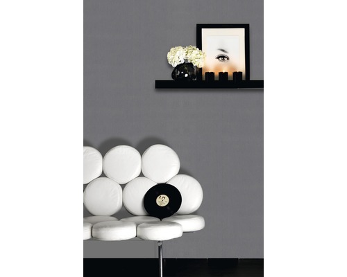 Szene mit einem weißen Stuhl, Schallplatte, Wandregal mit Dekoration und einem Porträt an einer grauen Wand