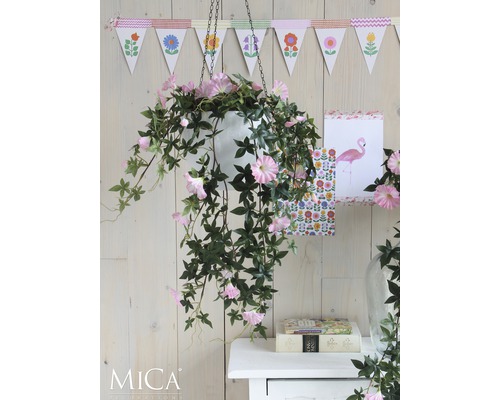 Plante suspendue décorative avec des fleurs roses dans un pot blanc devant un mur en bois