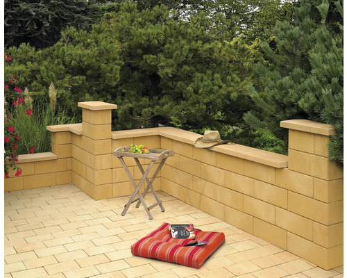 Terrasse avec murs en blocs de béton, table, coussin et chapeau