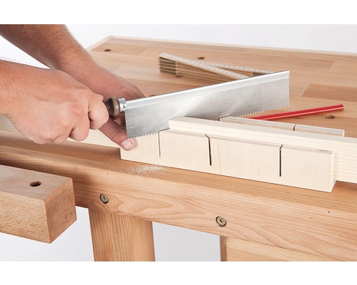 Artisan coupant du bois avec une scie à dos et une boîte à onglets sur un établi