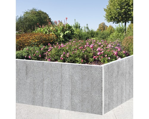 Jardinière surélevée en pierre avec des fleurs plantées dans le jardin