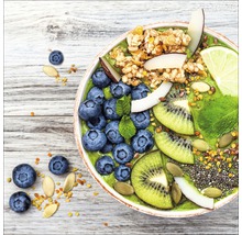 Nahaufnahme einer Schüssel mit Smoothie, garniert mit Blaubeeren, Kiwi, Kokosnuss, Limette und Müsli.