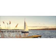 Segelboot auf dem See mit Steg im Abendlicht