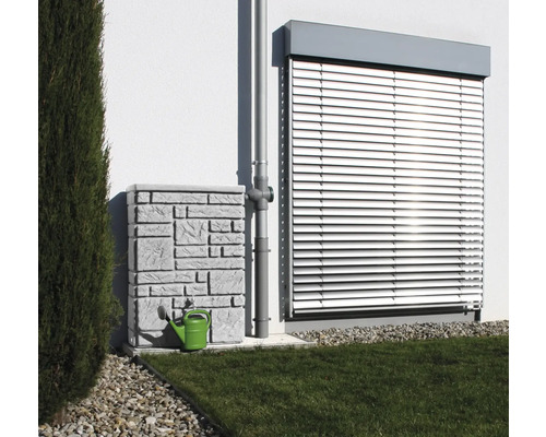 Récupérateur d''eau de pluie avec motif en pierre et arrosoir vert à côté d''une descente pluviale devant un mur de maison