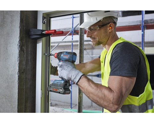 Un artisan utilise une visseuse à chocs sans fil sur un cadre de fenêtre sur un chantier de construction.
