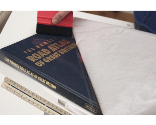 Film de protection pour livres appliqué sur un atlas routier avec une raclette