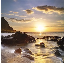 Ein Küstenlandschaftsbild mit Felsen im Wasser bei Sonnenuntergang.
