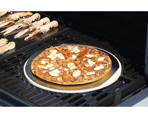 Sur un gril, une pizza est posée sur une pierre à pizza, entourée de scampis.