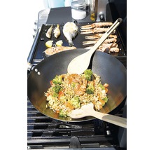 Wok mit Gemüse und Garnelen sowie Fisch und Meeresfrüchte auf einem Grill zubereitet.