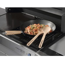 Ein Gasgrill mit einem Wok mit Garnelen und zwei Holzlöffeln.