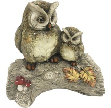 Dekorative Eulenfiguren auf Baumstamm mit Blättern und Pilzen