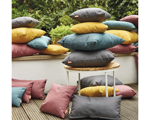 Scène avec des coussins d''extérieur empilés de différentes formes et couleurs sur une terrasse