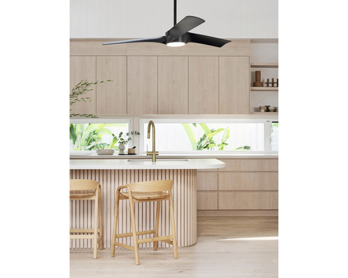 Cuisine lumineuse avec ventilateur de plafond, îlot de cuisine et tabourets de bar.