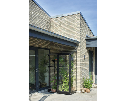 Anlehngewächshaus Halls Qube Lean-To 24 Sicherheitsglas 3 mm 65 x 127 cm schwarz Gewächshaus aus Glas und Metall mit Pflanzen vor einem Haus