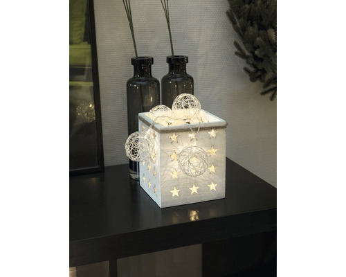 Boîte décorative en bois avec des étoiles et une guirlande lumineuse sur une table.