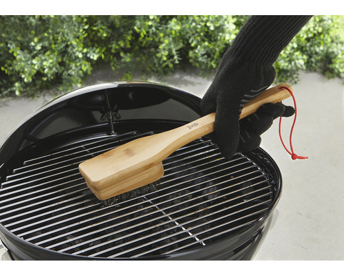 Eine Person reinigt einen Grillrost mit einer Grillbürste aus Bambus