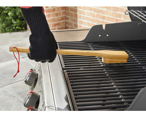Grillbürste mit Holzgriff reinigt einen Grillrost