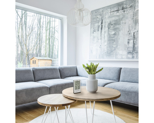 Salon avec canapé gris, tables rondes et station météo numérique