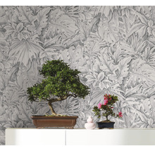 Papier peint décoratif avec motif de feuilles botaniques servant de toile de fond à deux bonsaïs sur une étagère