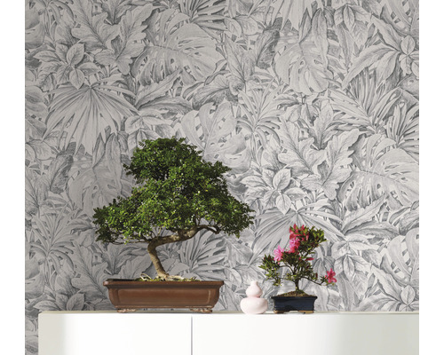 Papier peint décoratif avec motif de feuilles botaniques servant de toile de fond à deux bonsaïs sur une étagère