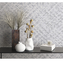 Dekorative Vasen und ein Stapel Bücher auf einem Regal vor einer Mosaikwand