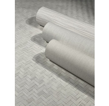 Drei Rollen textile Vliestapeten auf einem geflochtenen Untergrund.